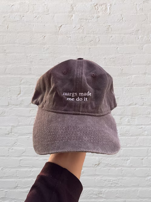 Citrus Huis "Margs Made Me Do It" cap featuring a casual black baseball hat with embroidered text, worn by a person.